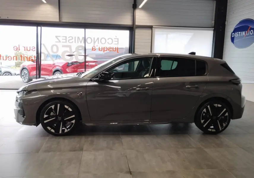 Profil côté gauche de la Peugeot 308 gris selenium 2026 avec jantes alliage 18 pouces et blason distinctif sur aile avant.