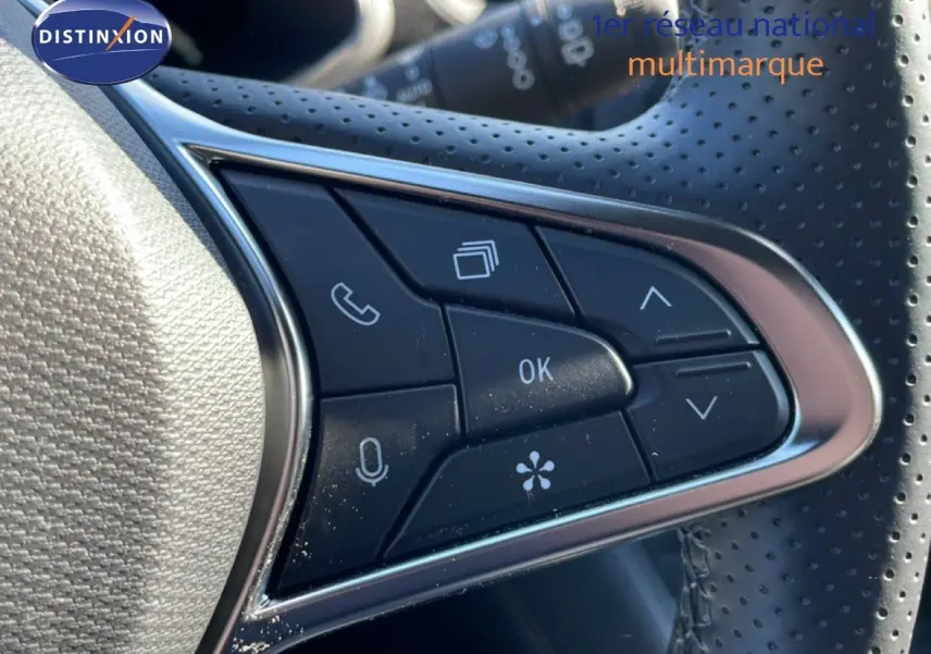 Gros plan sur les commandes multifonctions noires du volant perforé d’une Renault Symbioz 2025 finition Iconic.