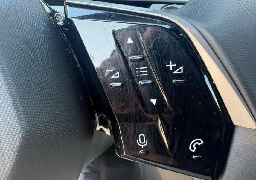 Gros plan sur les commandes vocales et audio au volant du Peugeot 3008 Hybrid gris, version 2025.