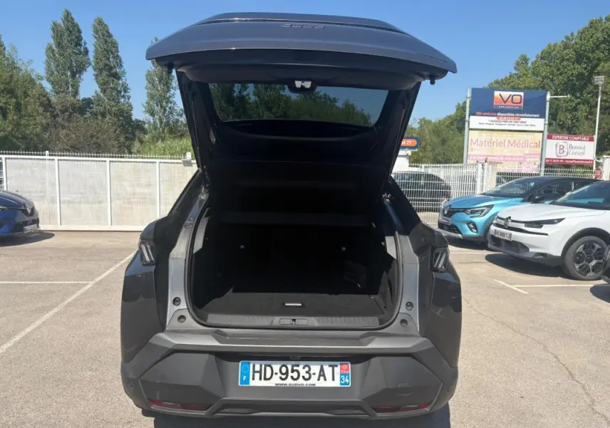 Vue arrière d'un Peugeot 3008 gris 2025 avec coffre ouvert, jantes alliage 18 pouces visibles au soleil.