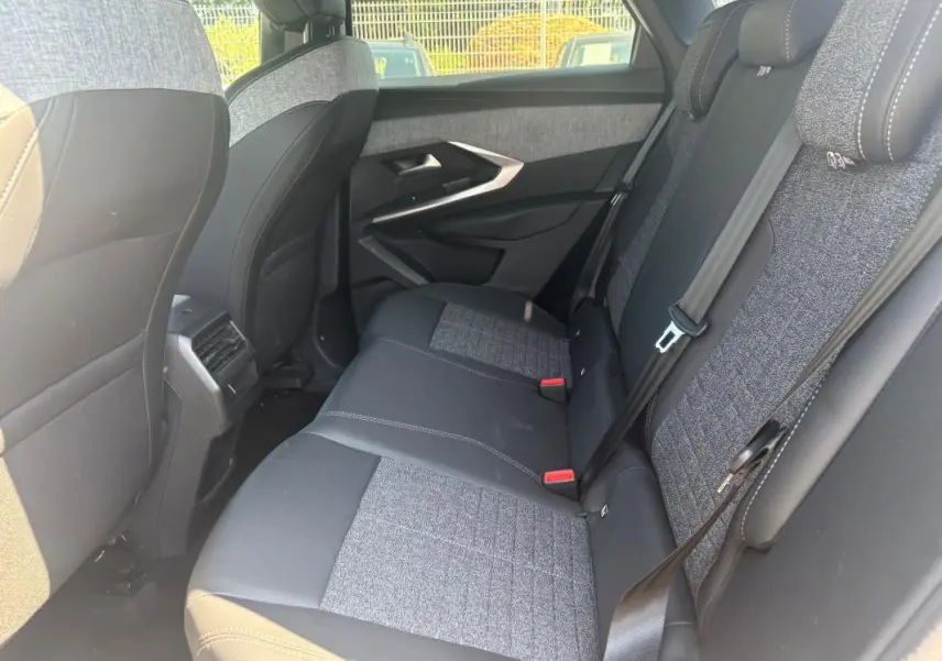 Vue intérieure côté droit des sièges arrière du Peugeot 3008 Hybrid 145 e-DCS6 Allure avec sellerie bi-matière grise et noire.