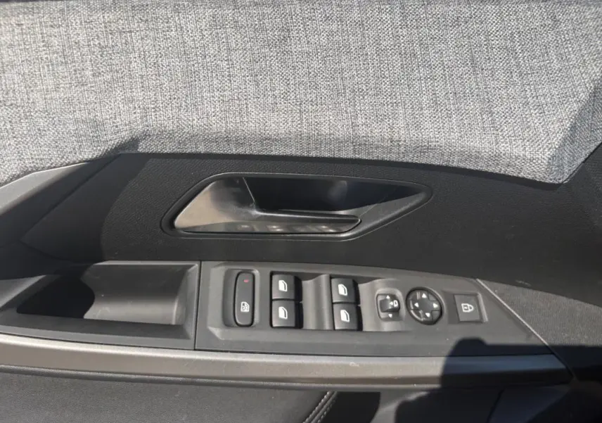 Vue du panneau de porte côté conducteur du Peugeot 3008 gris, avec commandes des vitres et rétroviseurs.