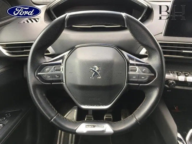 Gros plan sur le volant cuir Peugeot 3008 GT Line avec commandes multifonctions et logo lion au centre.