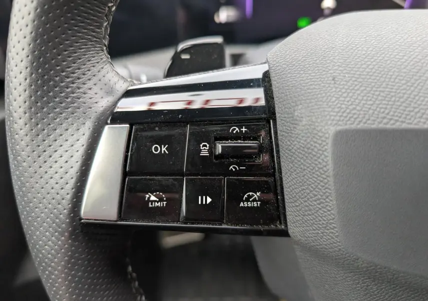 Gros plan sur les commandes à gauche du volant cuir perforé de l'Opel Astra 2024 gris métallisé.