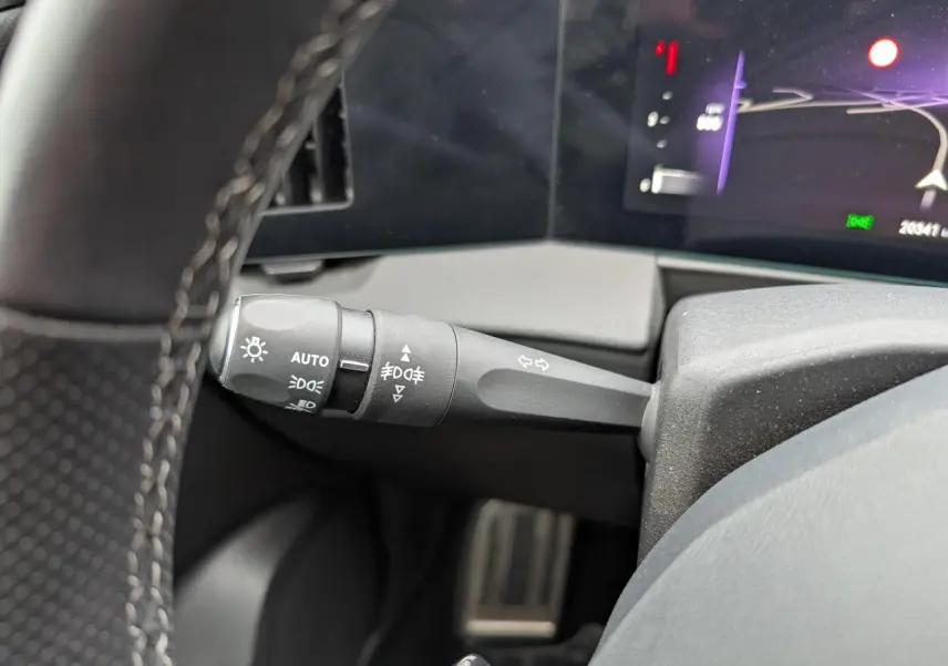 Gros plan sur la manette de commande d'éclairage à gauche du volant dans l'habitacle de l'Opel Astra 2024.