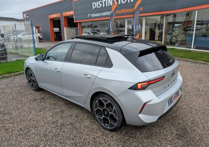 Opel Astra 2024 gris métallisé vue 3/4 arrière droit avec toit noir et jantes alliage diamantées.