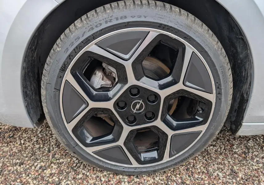 Gros plan sur la jante alliage 18 pouces pentagonale diamantée noire et grise d'une Opel Astra gris métallisé 2024.