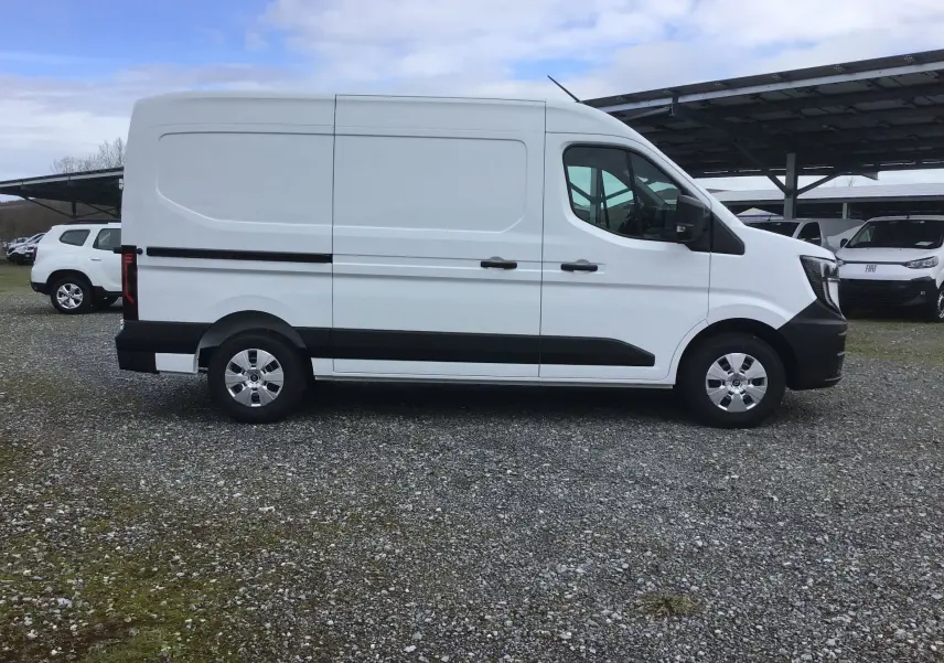 Vue de profil côté droit d’un Renault Master blanc L2H2 avec bande noire et jantes acier, stationné sur un sol gravillonné.