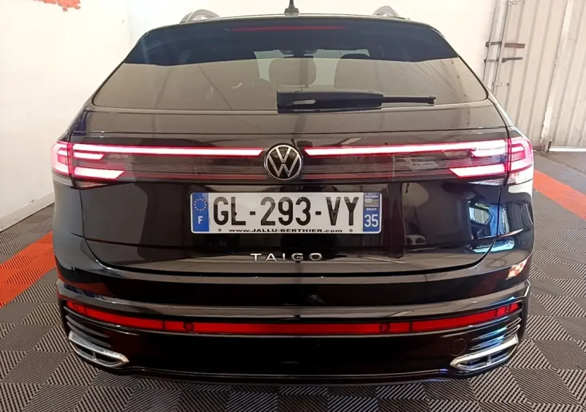 Vue arrière d’un Volkswagen Taigo noir 2023 avec feux LED allumés et double sortie d’échappement chromée.