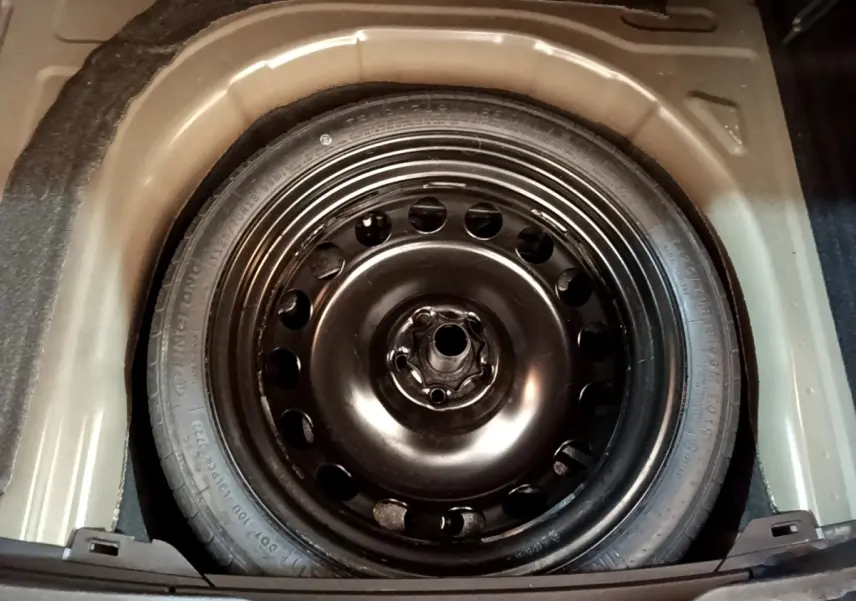 Vue plongeante sur la roue de secours noire en acier dans le coffre du Volkswagen Taigo 1.5 TSI 150 DSG R-Line 2023.