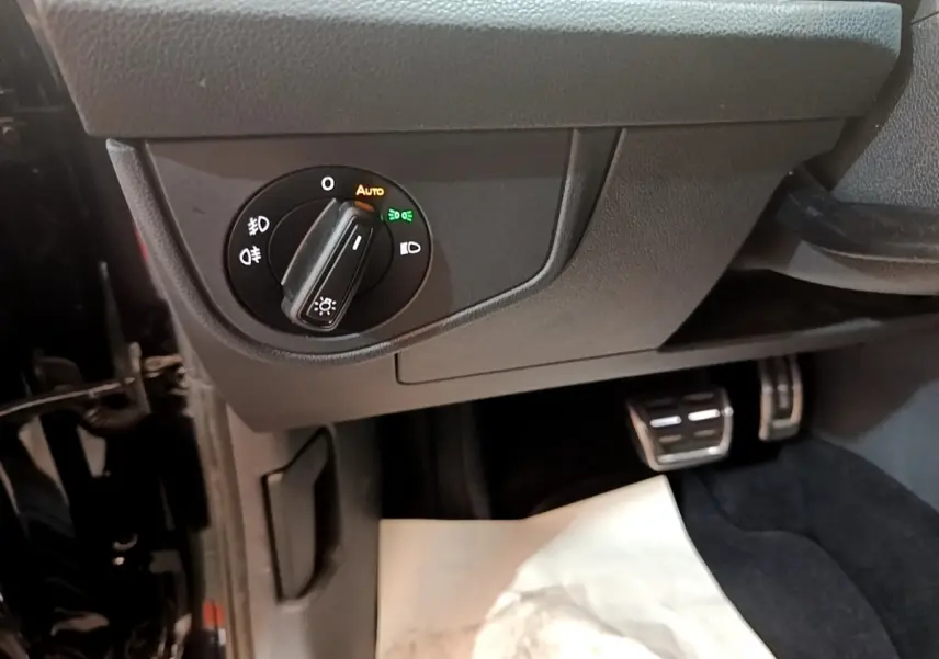 Détail du bouton de commande des phares sur le côté gauche du tableau de bord du Volkswagen Taigo noir 2023.