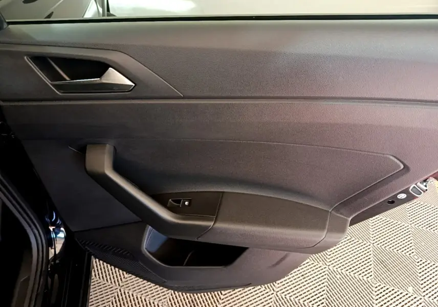 Vue intérieure de la porte côté gauche noire du Volkswagen Taigo 1.5 TSI 150 DSG R-Line avec poignée et commande de vitre.