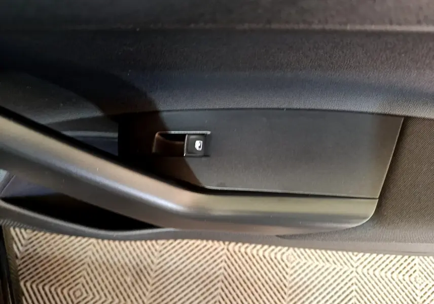 Gros plan sur la commande de lève-vitre côté gauche de la porte intérieure noire du Volkswagen Taigo 1.5 TSI R-Line 2023.