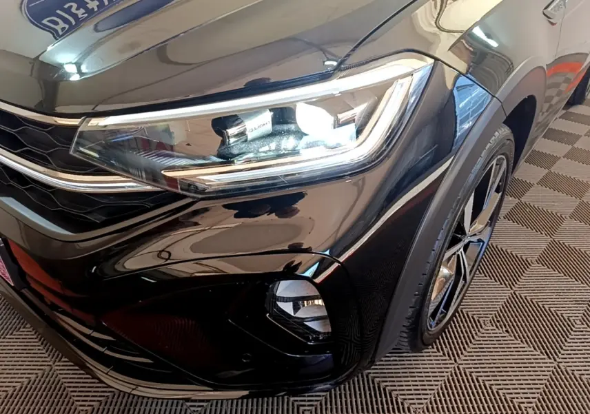 Gros plan sur l'avant droit noir brillant du Volkswagen Taigo 1.5 TSI 150 DSG R-Line avec phares LED et jante alliage.
