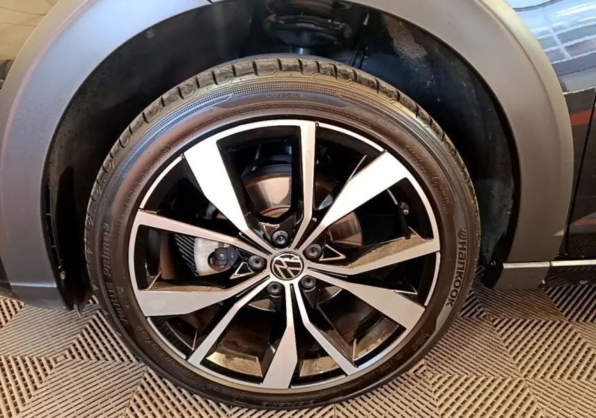 Gros plan sur la roue avant droite noire du Volkswagen Taigo 1.5 TSI 150 DSG R-Line avec jante alliage bicolore.