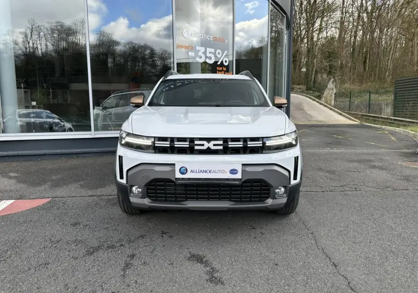 Vue avant du Dacia Duster blanc glacier 2025 avec calandre noire et projecteurs LED distinctifs.