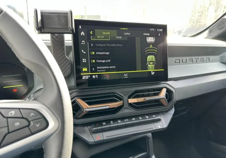 Vue intérieure du tableau de bord du Dacia Duster 2025, avec écran tactile central affichant les réglages de sécurité.