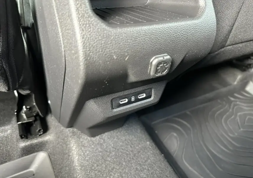 Détail intérieur montrant les ports USB-C et une prise 12V sous la console centrale du Dacia Duster blanc glacier.