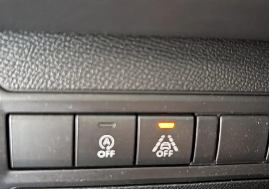 Gros plan sur les boutons de désactivation de l'arrêt auto et de l'alerte de franchissement de ligne dans une Peugeot 308 gris foncé de 2019.