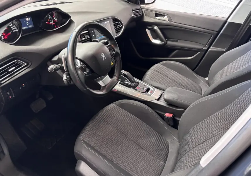Intérieur avant droit de la Peugeot 308 gris foncé, volant multifonction et console centrale avec boîte automatique visible.