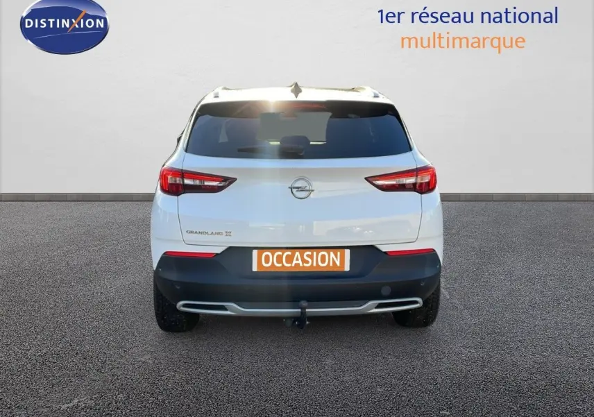 Vue arrière d'un Opel Grandland X blanc avec toit noir, équipé d'un attelage et d'une plaque "OCCASION".