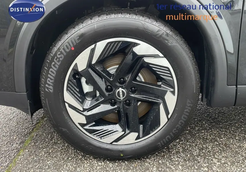 Gros plan sur la roue avant gauche du Nissan Qashqai noir perle métal avec jante alliage bicolore distinctive.
