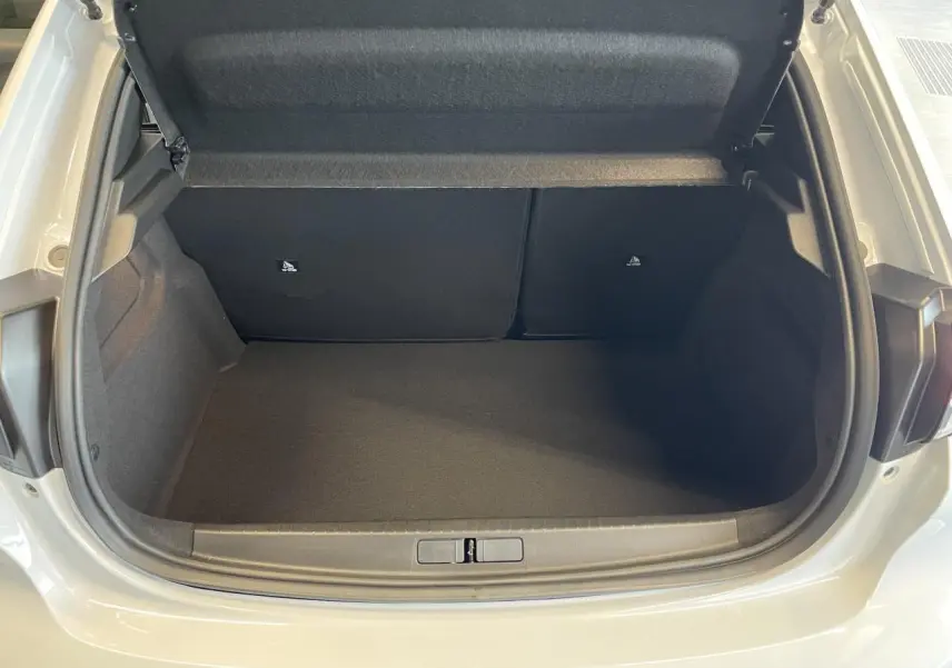 Coffre ouvert vu de l'arrière d'une Peugeot 208 blanche Okenite, montrant l'espace de rangement vide et la doublure noire.