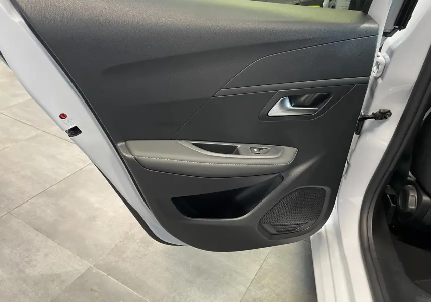 Vue rapprochée de la porte arrière gauche blanche okenite du Peugeot 208 1.2i Hybrid avec garniture noire et accoudoir gris clair.