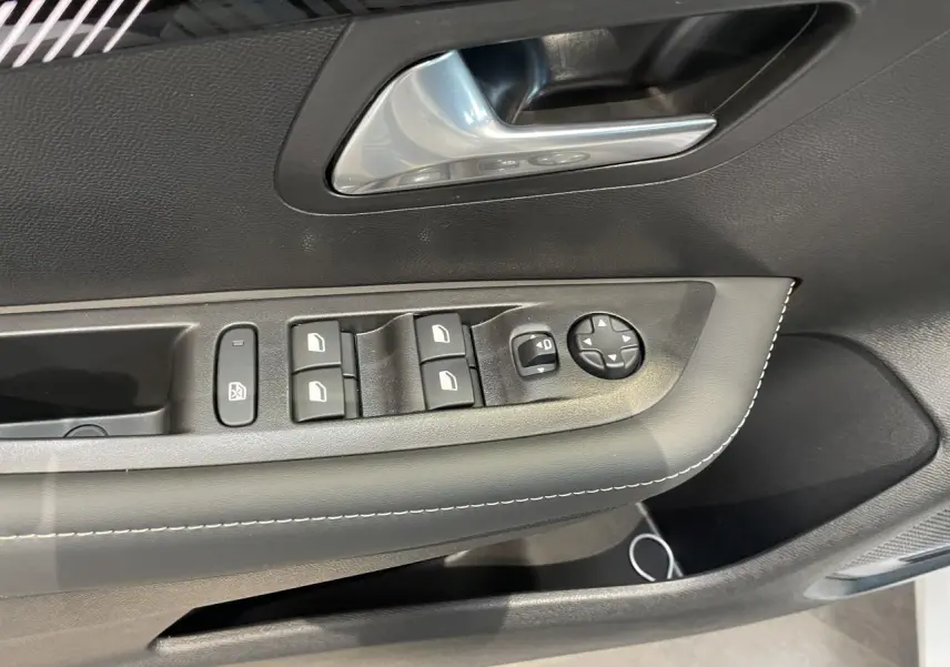 Gros plan sur la porte avant gauche de la Peugeot 208 blanche, montrant les commandes de vitres et le bouton de réglage des rétroviseurs.
