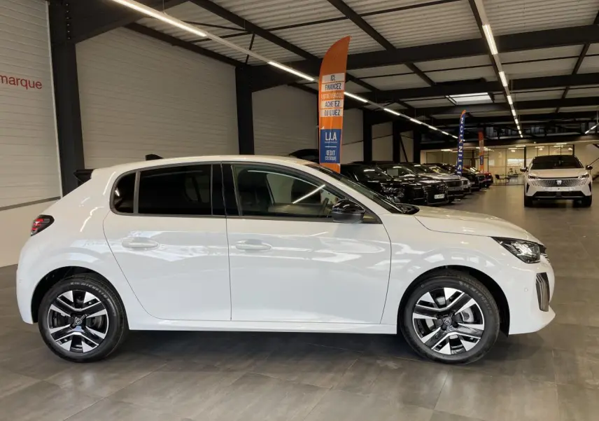Peugeot 208 blanche okenite vue de profil côté gauche en intérieur avec jantes alliage bi-tons et rétroviseurs noirs.
