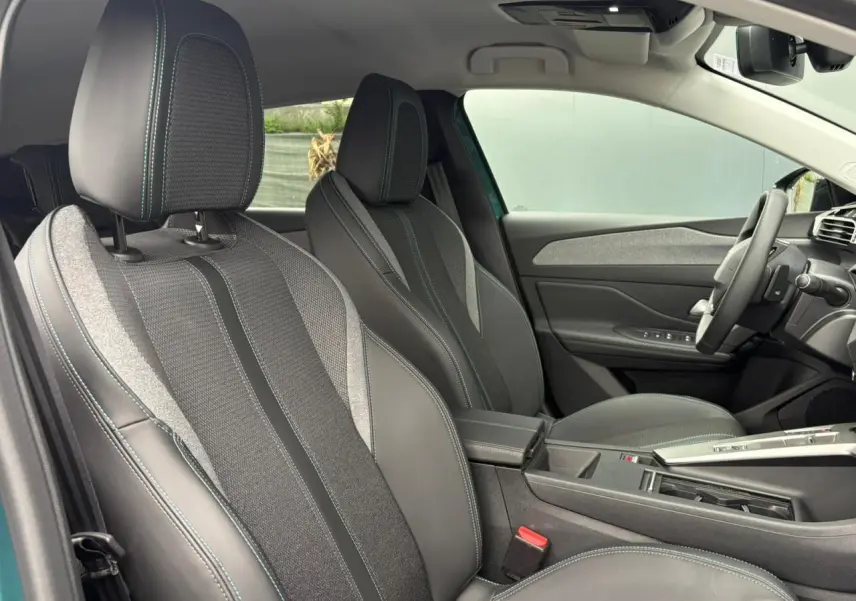 Vue intérieure côté avant droit du Peugeot 308 SW Hybrid 145 Allure, sièges tri matières gris avec surpiqûres bleues.