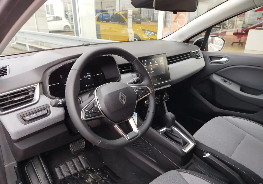 Intérieur avant droit de la Renault Clio TCE 90CH X-TRONIC Evolution 2025 avec tableau de bord gris et volant multifonction.