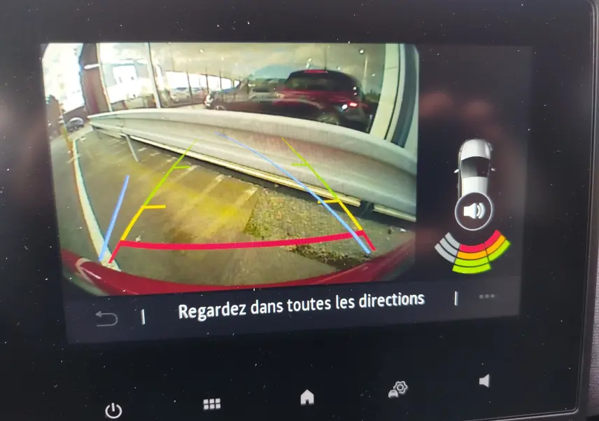 Vue caméra de recul de la Renault Clio rouge flamme, avec lignes d'aide au stationnement et capteurs d'obstacles actifs.