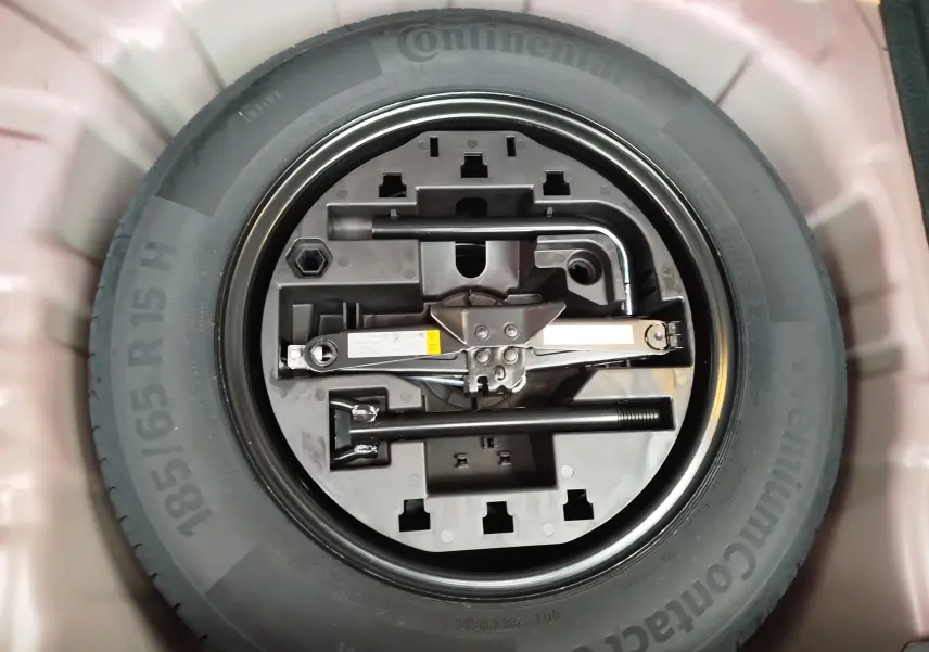 Gros plan sur la roue de secours et les outils de bord du coffre d'une Renault Clio rouge flamme 2025.