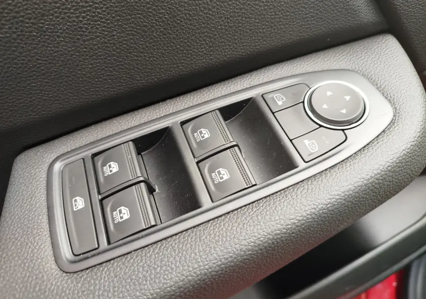 Commande des vitres électriques et réglage des rétroviseurs sur la porte côté conducteur d'une Renault Clio rouge flamme.