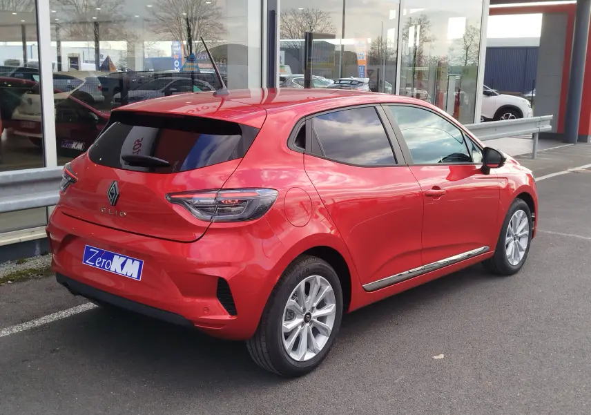 Vue 3/4 arrière droite d'une Renault Clio rouge flamme avec vitres teintées et jantes alliage argentées.