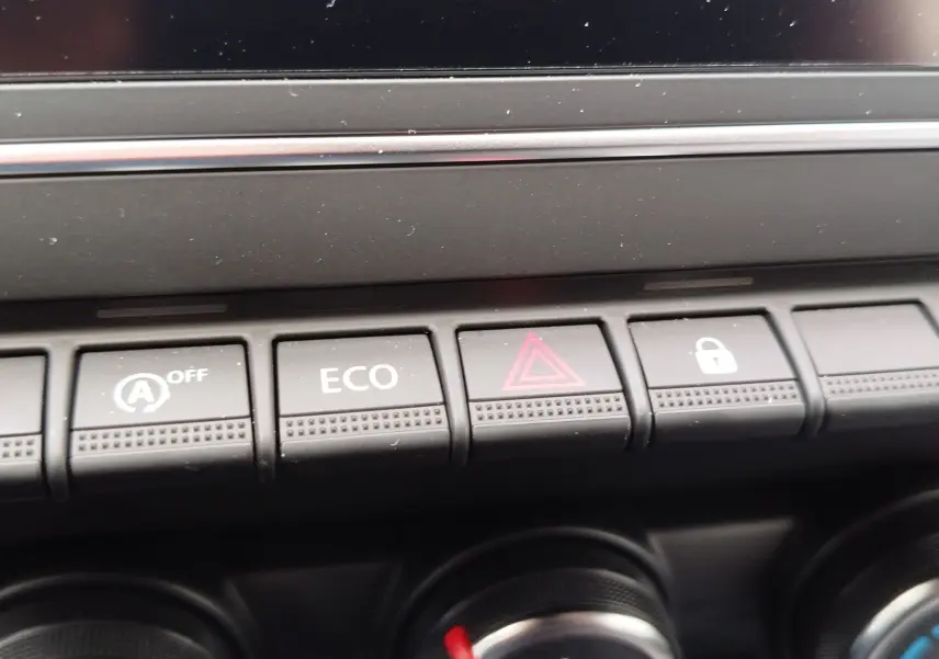 Gros plan sur les boutons de commande du tableau de bord de la Renault Clio rouge flamme 2025, avec mode ECO et alerte.