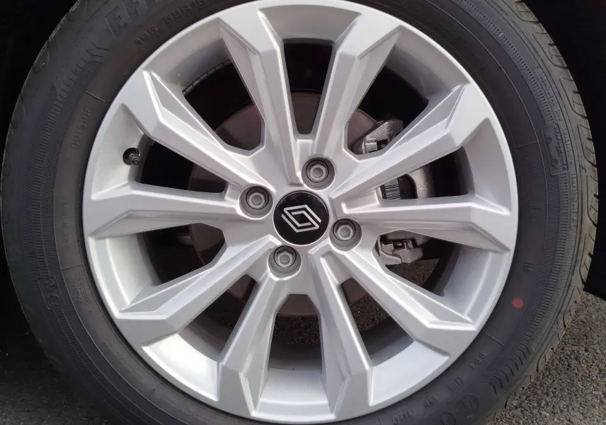 Gros plan sur la jante alliage argentée d'une Renault Clio rouge flamme, avec logo Renault au centre.