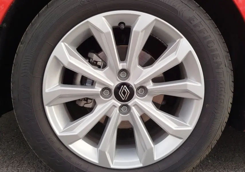 Gros plan sur la jante argentée à dix branches de la Renault Clio rouge flamme, avec logo Renault au centre.