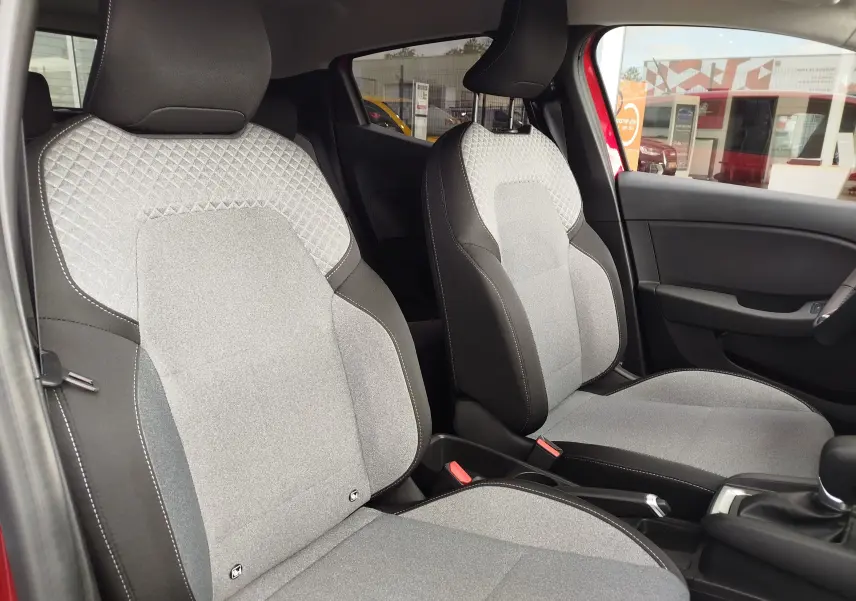 Vue intérieure sur les sièges avant gris clair et noir de la Renault Clio TCE 90CH X-TRONIC Evolution 2025 rouge flamme.