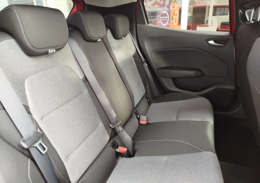 Vue intérieure de la banquette arrière grise et noire de la Renault Clio 2025 rouge flamme, côté droit avec ceintures et appuie-têtes.