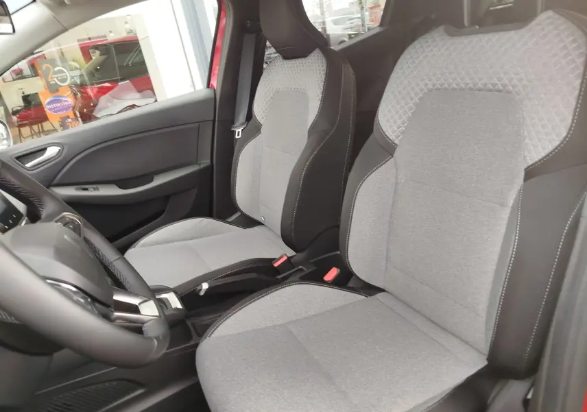 Intérieur de la Renault Clio TCE 90CH X-TRONIC Evolution 2025, sièges tissu gris clair avec surpiqûres noires, vue côté conducteur.