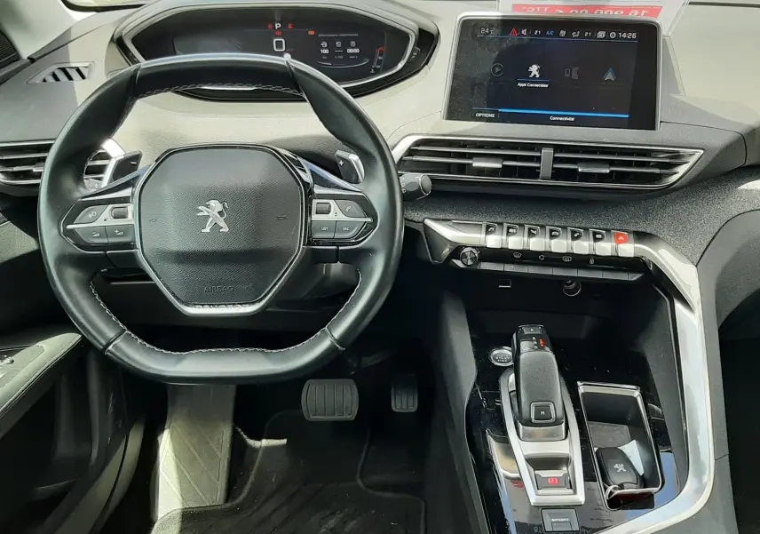 Vue intérieure du poste de conduite du Peugeot 3008 gris, avec volant compact, écran tactile central et levier de boîte automatique.