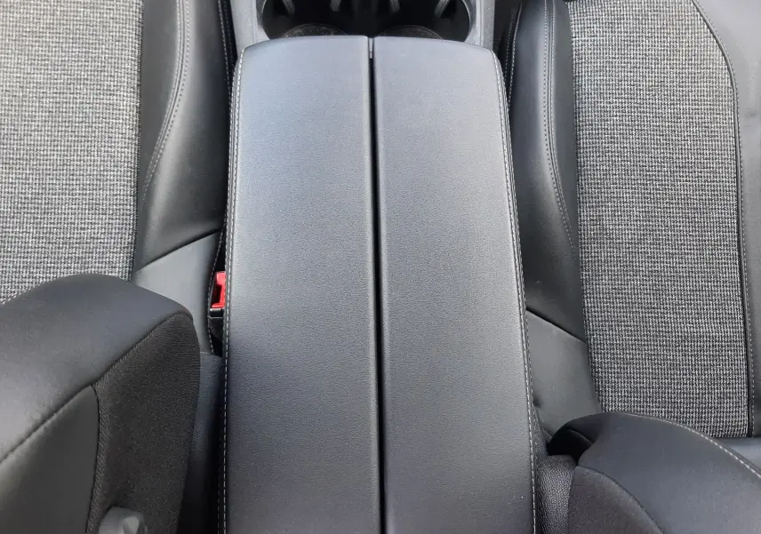 Vue plongeante sur l'accoudoir central en cuir noir et tissu gris des sièges avant du Peugeot 3008 gris 2020.