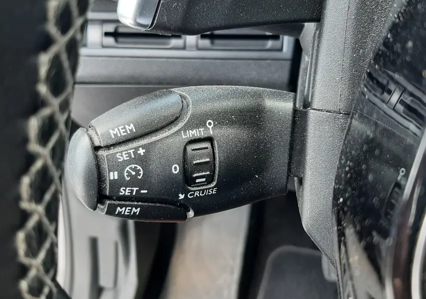 Gros plan sur la commande de régulateur de vitesse du Peugeot 3008 gris, côté gauche du volant.