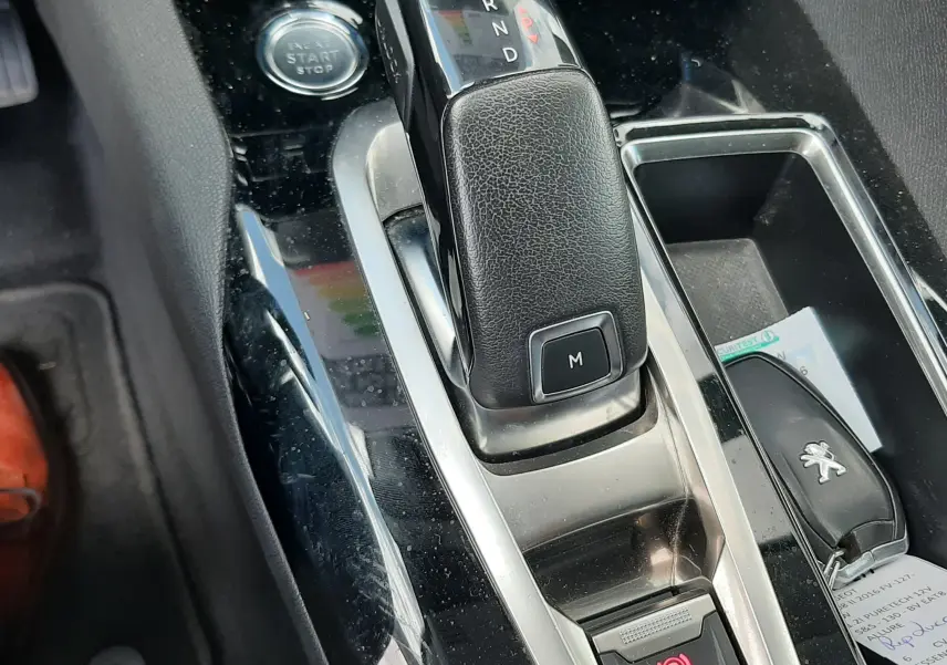 Gros plan sur la console centrale noire du Peugeot 3008 gris 2020, avec levier de boîte auto et bouton start/stop visible.