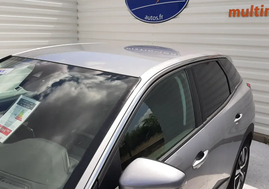 Vue 3/4 avant droit d'un Peugeot 3008 gris métallisé garé devant un mur blanc avec logo Distinxion visible.