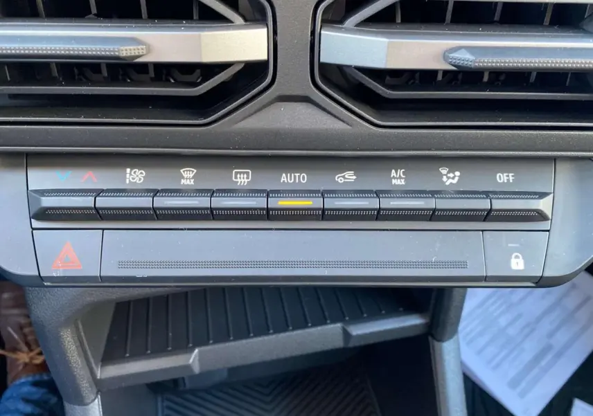 Gros plan sur la console centrale du Dacia Duster 2024 montrant les commandes de climatisation automatique.
