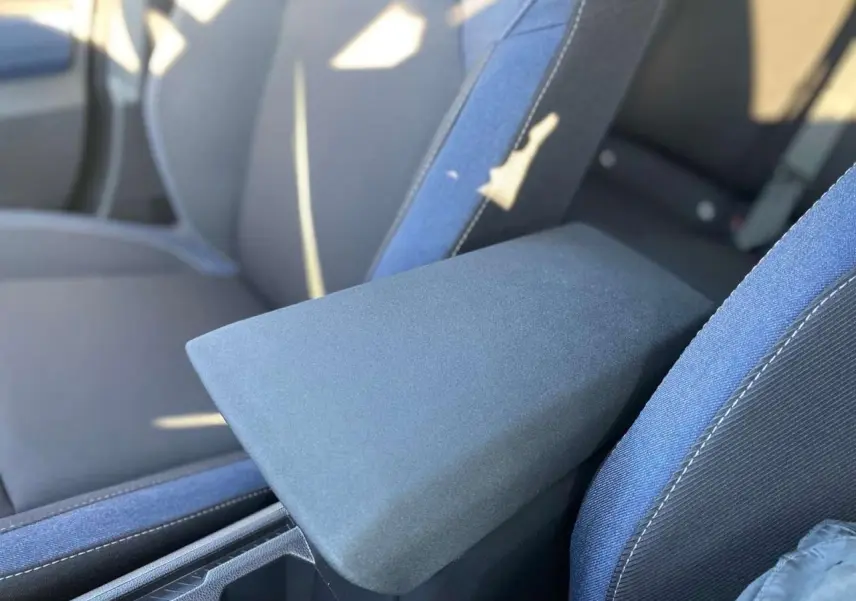 Accoudoir central en tissu gris entre les sièges avant bleu foncé du Dacia Duster 2024.