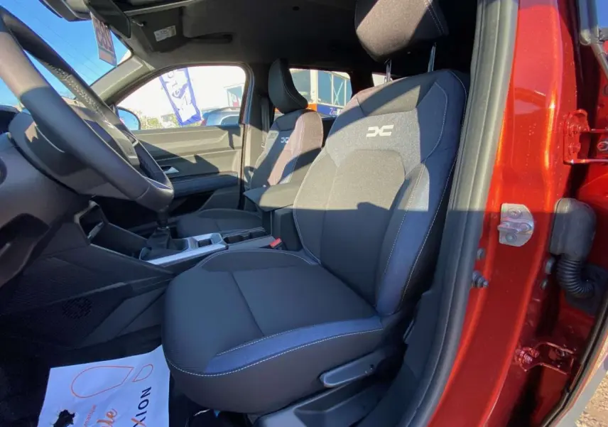 Vue intérieure côté conducteur du Dacia Duster 2024 brun terracotta, mettant en valeur les sièges tissu avec logo Extreme.